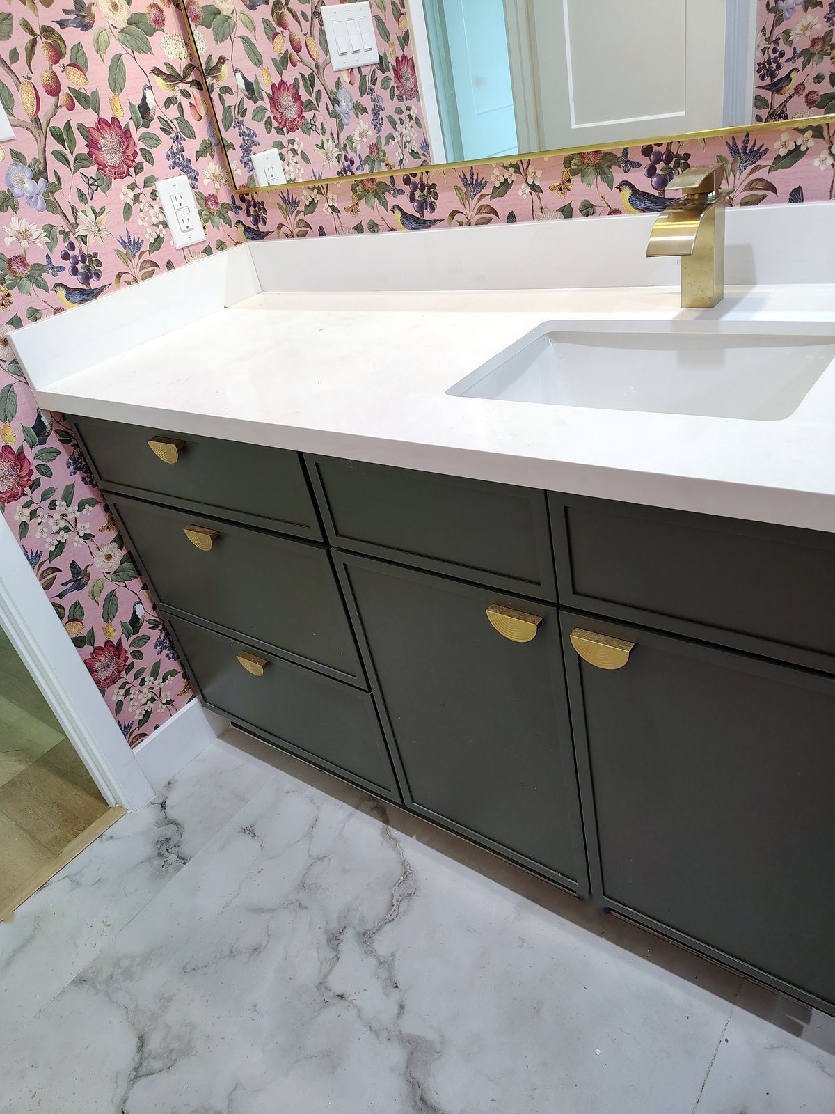 Dark green shaker vanity with brushed-gold half-moon pulls, a white quartz top and an undermount sink.